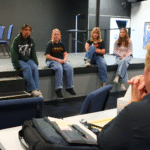 Students performing Frozen Jr. on stage with Arendelle castle backdrop and sparkling snow effects