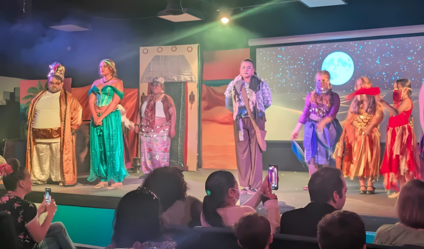 Kids in rehearsal or mid-performance during a youth musical theater production, showing emotion, teamwork, and excitement on stage.